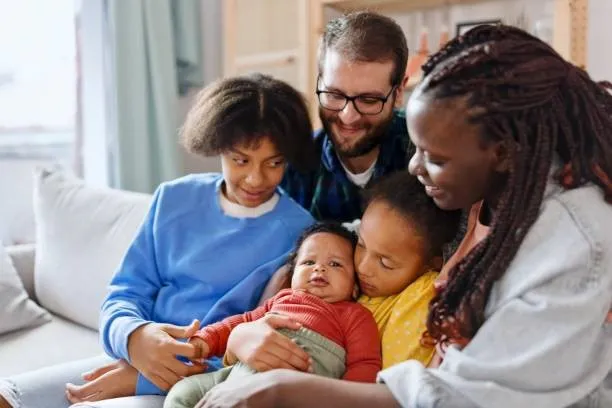 a family with man, woman and three children sitting on a sofa