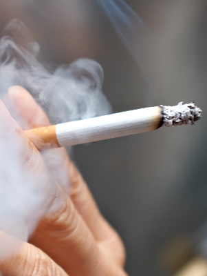 A close up of a man's hands holding a smoking cigarette